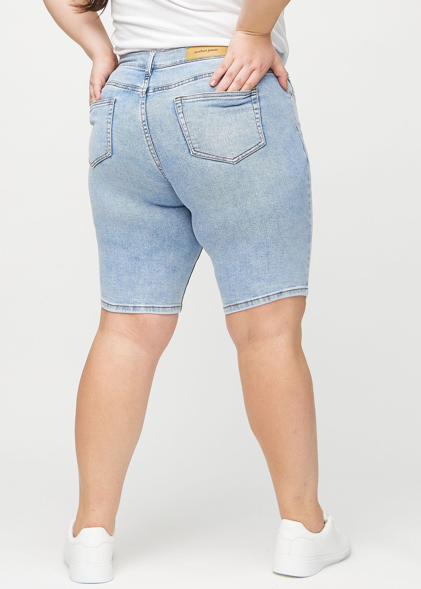 Lys denim skinny middle shorts set bagfra på en plus-size model, så man kan se hele produktet.